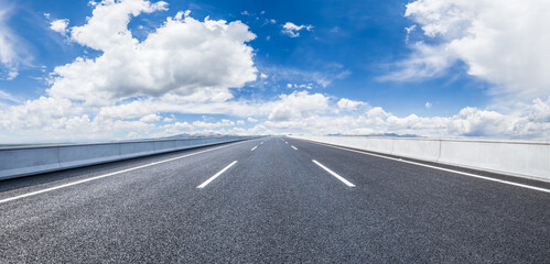 Asphalt highway road and sky clouds natural background. Panoramic view.