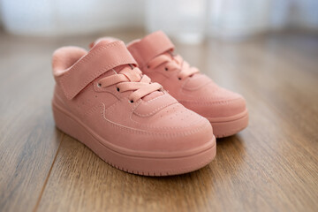 Child's pink sneakers on wooden floor. Cute girl's shoes on floor - 761539215