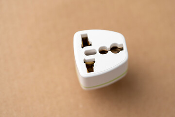 A white fork with a green stripe on it. The plug is on a brown surface, the adapter is a travel...
