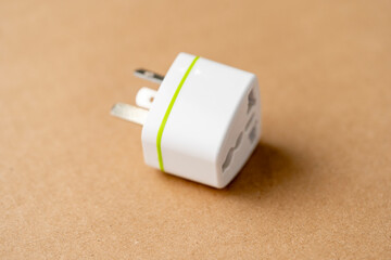 A white fork with a green stripe on it. The plug is on a brown surface, the adapter is a travel...