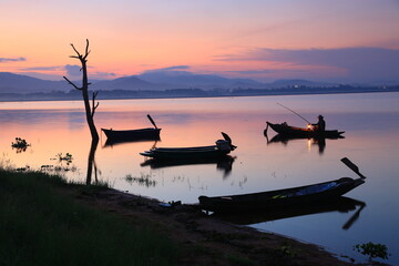  Silhouette fisherman on boat over Bang Phra reservoir during sunrise Sriracha ,Chonburi,Thailand 