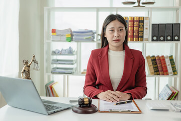 Obraz na płótnie Canvas Asian female lawyer working in office or court with hammer and justice pad on table, online legal advice with new laws of real estate business. Law, legal service, advice, justice.
