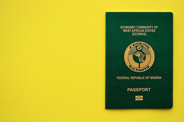 Green Nigerian passport on yellow background close up. Tourism and citizenship concept