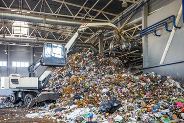 Excavator on primary sorting of garbage at waste processing plant. Separate garbage collection....