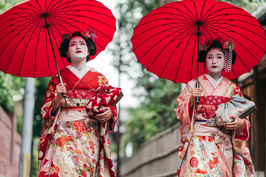 In the heart of Kyoto, geishas with red umbrellas exude a regal presence, their kimonos a canvas of cultural stories. They represent the living art of Japanese heritage