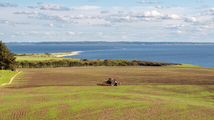 Southeast coast of Livo island with tractor on farmland, Limfjord, Nordjylland, Denmark
