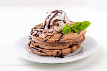 Stack of chocolate belgian waffles with ice cream and chocolate topping. Breakfast waffles with gelato, chocolate sauce drizzles and mint