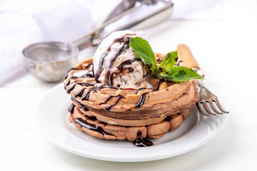 Stack of chocolate belgian waffles with ice cream and chocolate topping. Breakfast waffles with gelato, chocolate sauce drizzles and mint