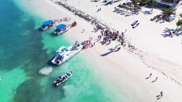 People board a tourist catamaran to embark on a tour of tropical islands with exotic beaches and turquoise lagoon, Dominican Republic, Caribbean Sea. A bird's eye view.