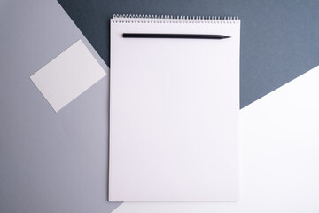 Spiral notepad on the table, business card and laptop. Business, stationery or education concept: image of an open notebook with blank pages
