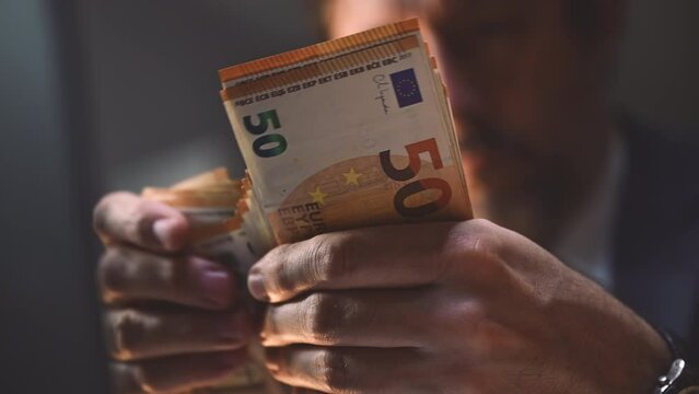 Closeup of businessman counting euro banknotes cash money in office late at night
