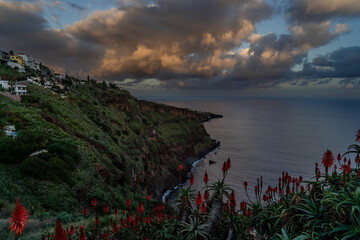 A serene view of a Village rocky coast , under a dusk sky with fluffy clouds Colorful sunset at...