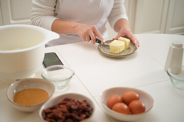 Close-up of woman's hands cutting butter with knife in kitchen. Process of cooking pecan pie in home kitchen for American Thanksgiving Day.