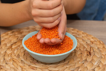 Hands Pouring Red Lentils into Bowl. Hands overflowing with vibrant red lentils over a bowl.