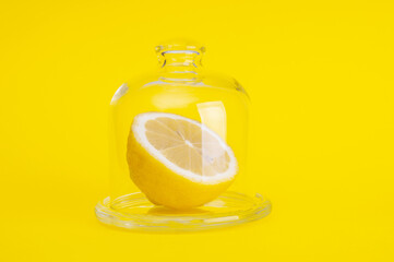 Sliced fresh lemon in glass case on yellow background