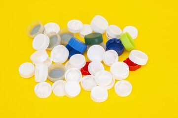 Pile of plastic caps from soda bottle on a yellow background