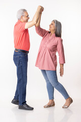 Full length of senior couple dancing on white background