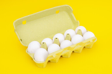Cardboard egg rack with eggs on a yellow background