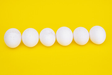 Row of chicken eggs on a yellow background