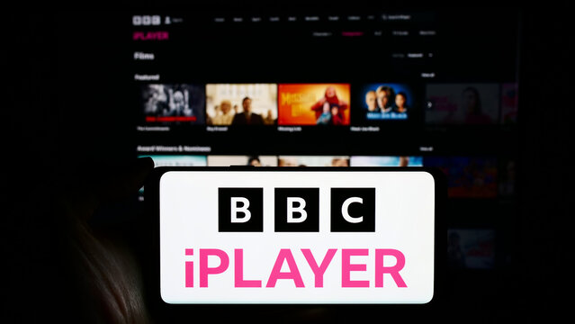 Stuttgart, Germany - 03-07-2024: Person holding cellphone with logo of British video on demand service BBC iPlayer in front of business webpage. Focus on phone display.