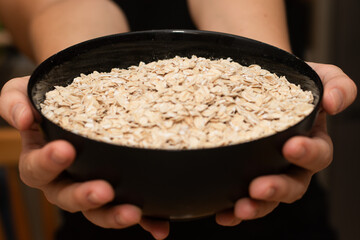 Holding a Bowl Full of Rolled Oats. Hands securely holding a bowl overflowing with whole rolled...