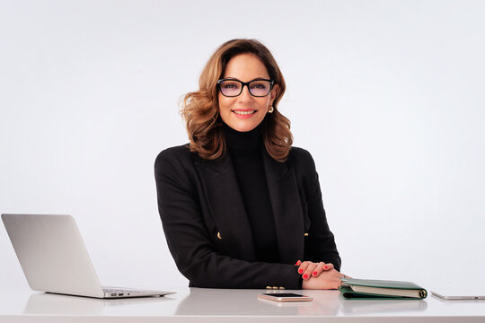 Mature woman businesswoman sitting at desk and using laptop against isolated background