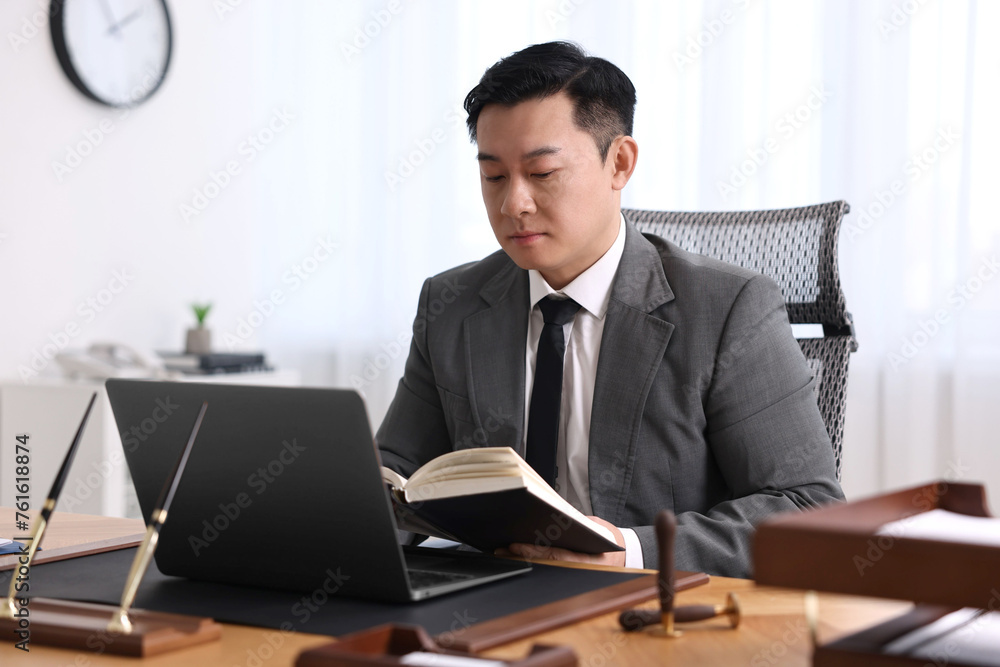 Sticker Notary working with laptop and book at wooden table in office