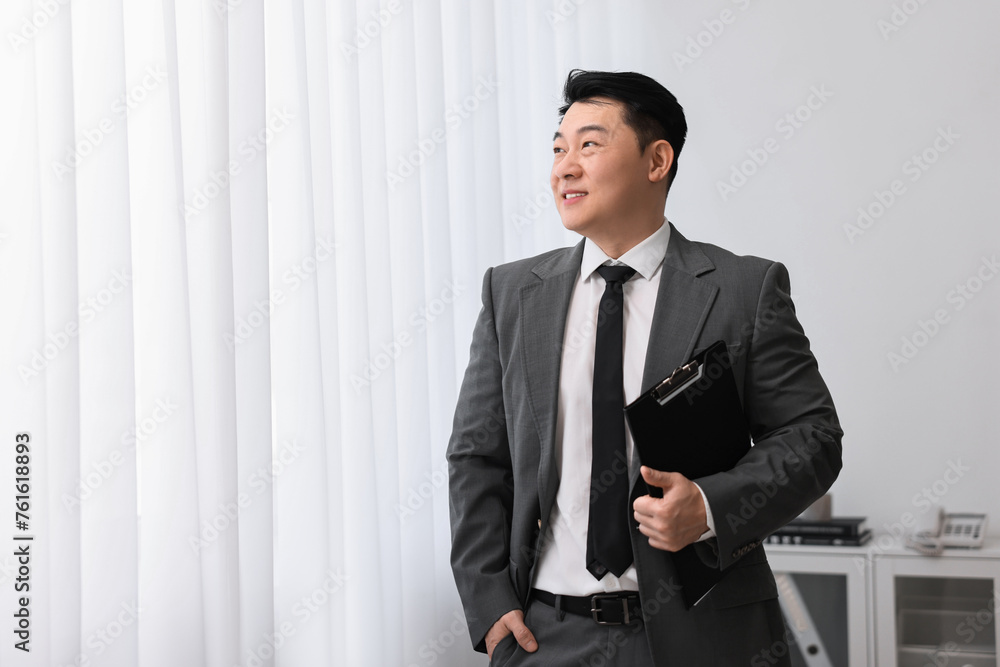 Wall mural Portrait of happy notary with clipboard indoors, space for text