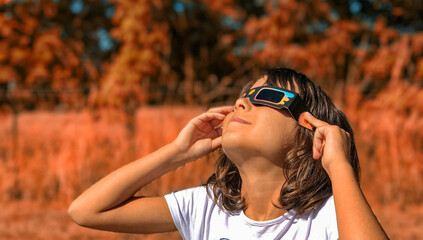A young girl looking at the sun during a solar eclipse on a country park, family outdoor activity - obrazy, fototapety, plakaty