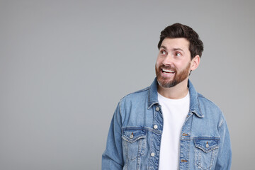 Portrait of happy surprised man on grey background, space for text