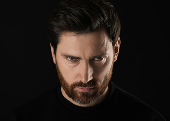 Fototapeta premium Evil eye. Man with scary eyes on black background, closeup