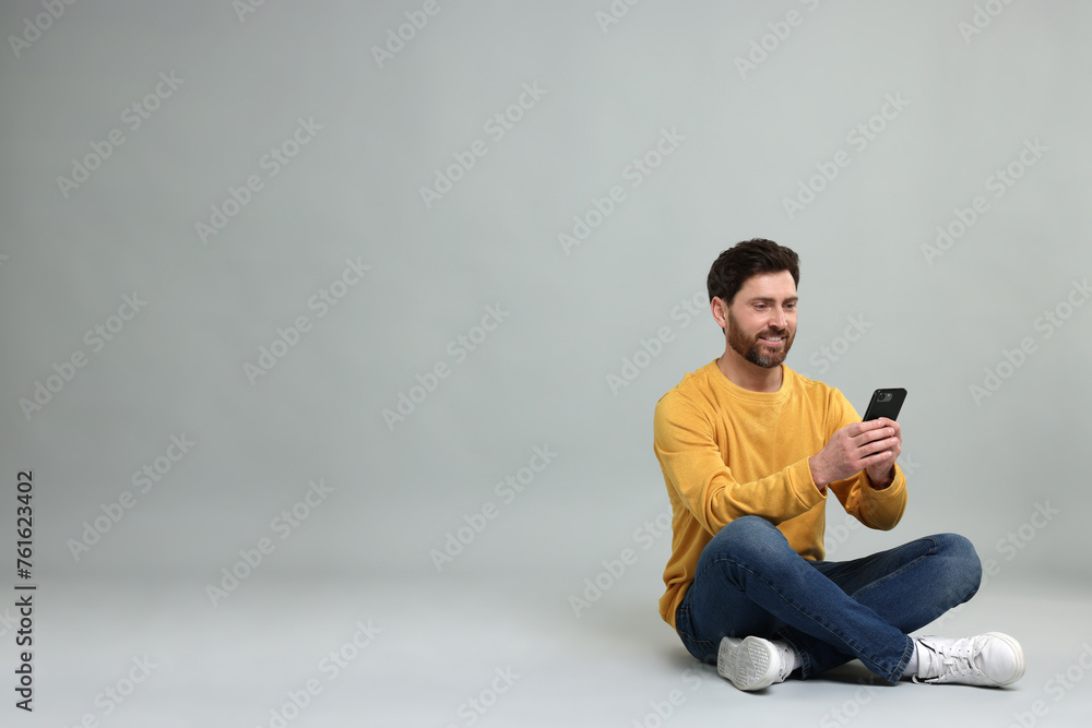 Aufkleber smiling man with smartphone on grey background. space for text