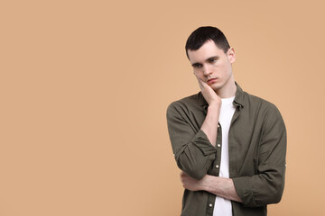 Portrait of sad man on beige background, space for text