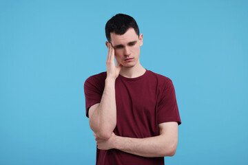 Portrait of sad man on light blue background
