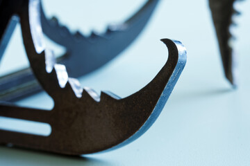 Fragment of a metal professional mountaineering assault hook for rock climbing. Light background....