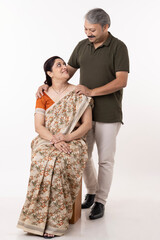 Portrait of smiling Indian couple with arms around on white background