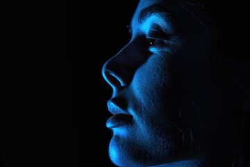 A profile of a person's face illuminated by blue light, showing a contemplative or emotional moment