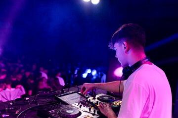 Rear side view of a dj working on a discotheque