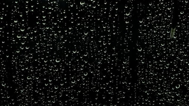 ガラス窓に落ちる雨と水滴　黒色の背景