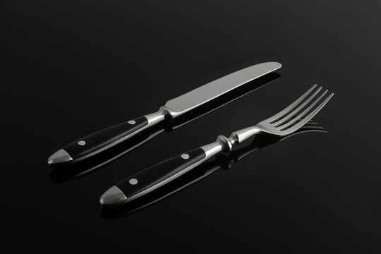 Vintage fork and knife on a black background with reflection.