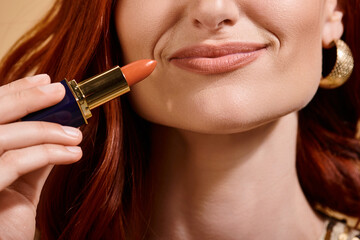 cropped view of woman smiling and applying nude lipstick on beige background, makeup product - Powered by Adobe