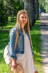 A young woman with braided hair enjoys a sunny walk in the park, embodying a casual, carefree...