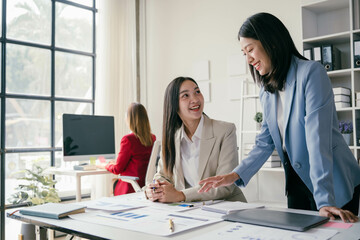 Three women are sitting at a desk, one of them is smiling