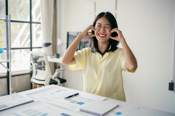 A woman is sitting at a desk with a yellow shirt on and smiling