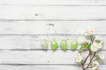Easter eggs in a row and decorative cherry branch on a white wooden table. Top view, flat lay, copy space - 761644256
