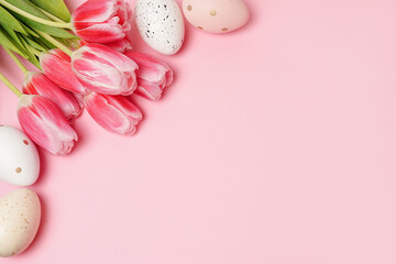 Colorful Easter eggs with pink bright tulips on pink background with copy space