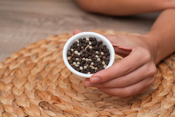 Bowl of Whole Peppercorns in a Female Hand. Gently holding a ramekin filled with assorted whole...