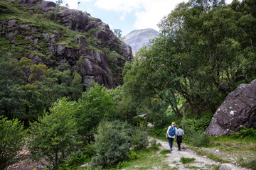 Fototapeta na wymiar Two people on the mountain path on Ben Nevis leading to Steall waterfall. Scottish highlands on a summer's day