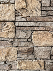 The wall is lined with decorative stone, beautiful seams, background. For the facade of the house, fence