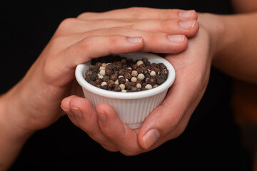Bowl of Whole Peppercorns in a Female Hands. Gently holding a ramekin filled with assorted whole peppercorns.